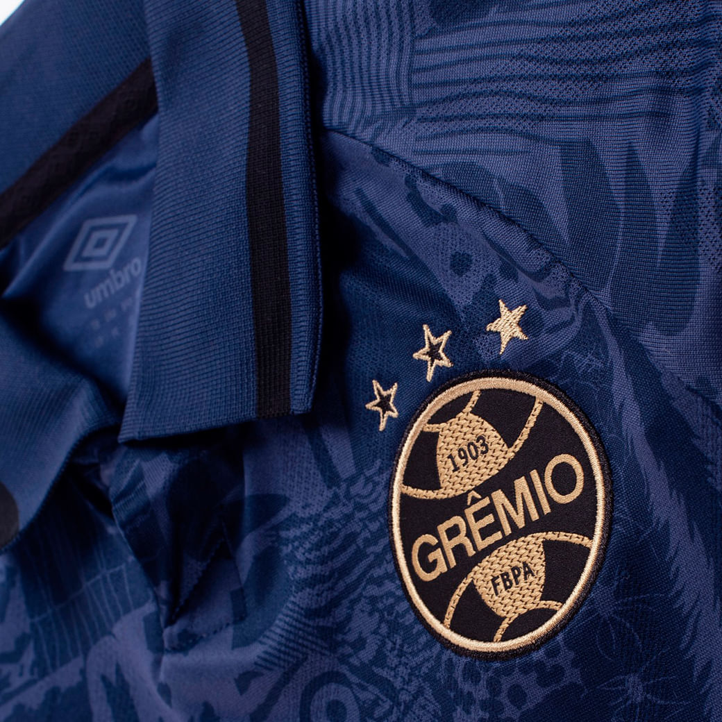 Close no escudo bordado da camisa infantil oficial Grêmio 2025 Umbro na cor marinho